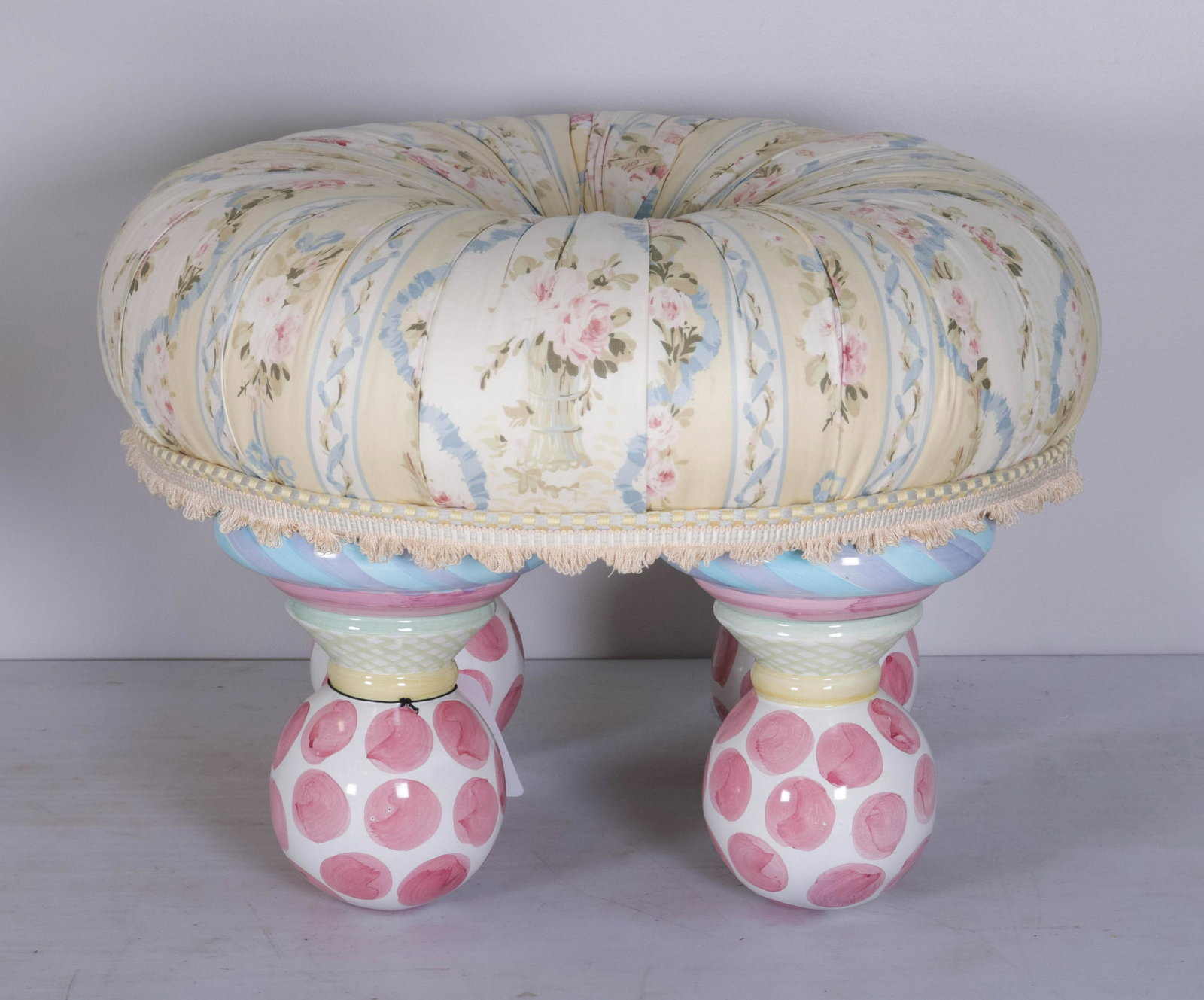 Mackenzie Childs Footed Tuffet Stool: Mackenzie Childs footed tuffet stool, raised on painted ball feet, in floral printed gathered fabric with silk fringe trim, 22" dia x 14" high, stain and button center.