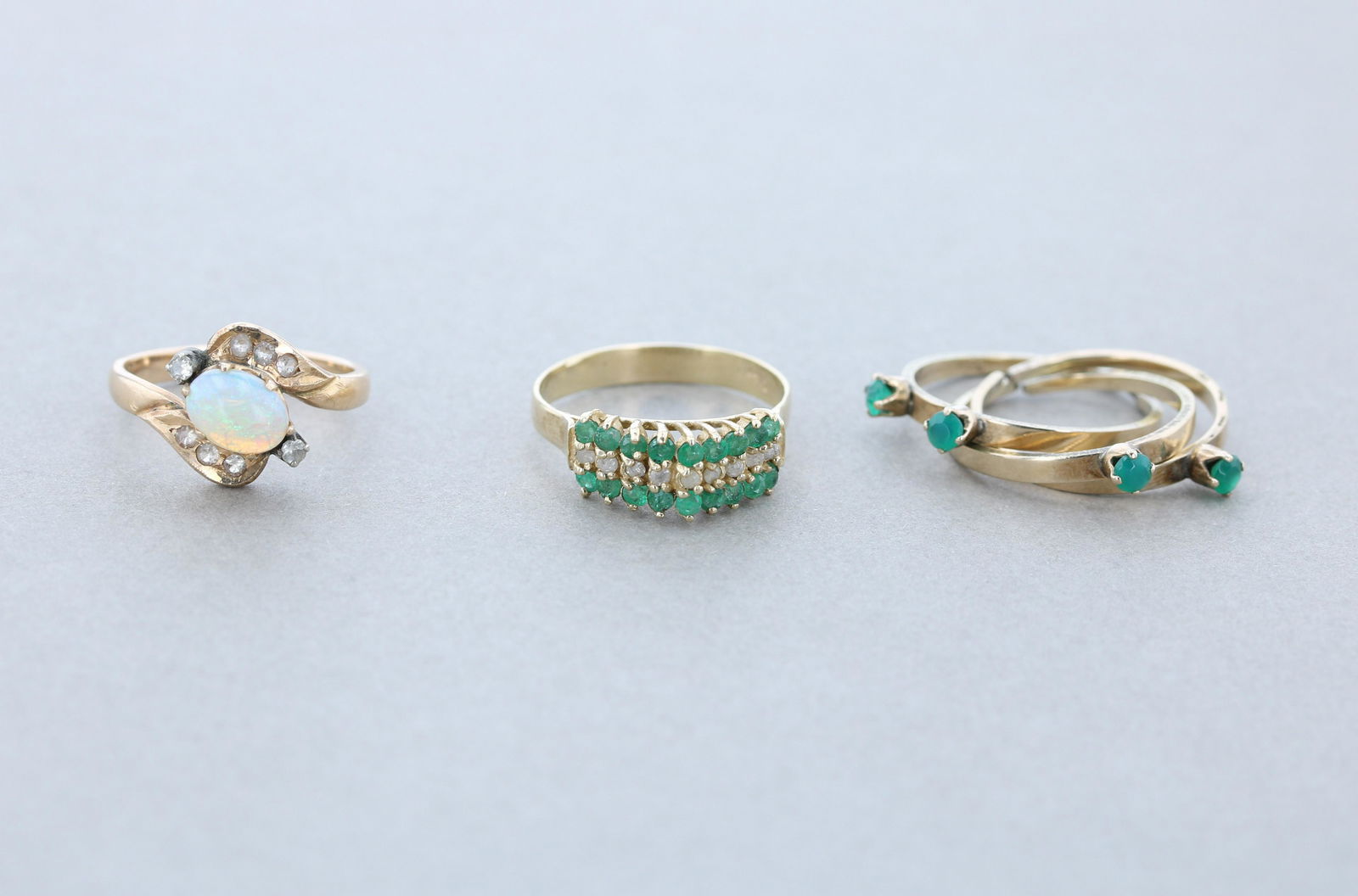 (3) Gold Rings: (1) 14K Emerald and diamond band, Sz.8, set with 9 small round diamonds and 18 small round emeralds. (1) marked 14K Yellow gold vintage opal 7.7 x 5.92 mm ring with clear stones, SZ 7, and (1) set of
