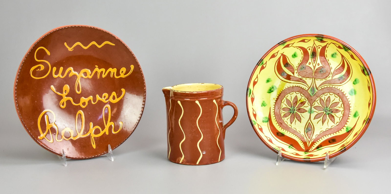 (3) Pcs James Seagreaves and Style Pottery: (3) Pcs James Seagreaves and style pottery to include Seagreaves redware plate with heart and flower sgraffito decoration, 10" diam, redware pitcher in yellow slip decoration, 6" h and L. Breininger r