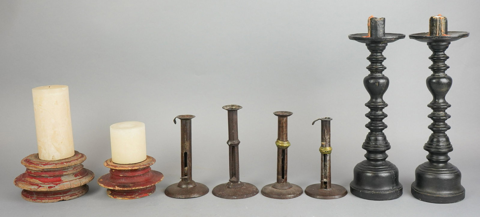 (4) Pair Candlesticks: (4) Pair candlesticks to include (2) pairs iron candlesticks, (1) missing push up lever, (1) pair composite painted sticks, in primitive style, 14-1/2" h and pair primitive red painted wood candle spi