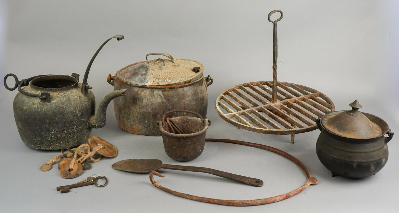 Cast Iron Cooking Implements: Cast iron cooking implements to include cast iron tin covered dutch oven on swing handle, 11" x 8-1/2", covered miniature cauldron, lid not matched, on tri foot and swing handle, approx 6" x 6", smelt