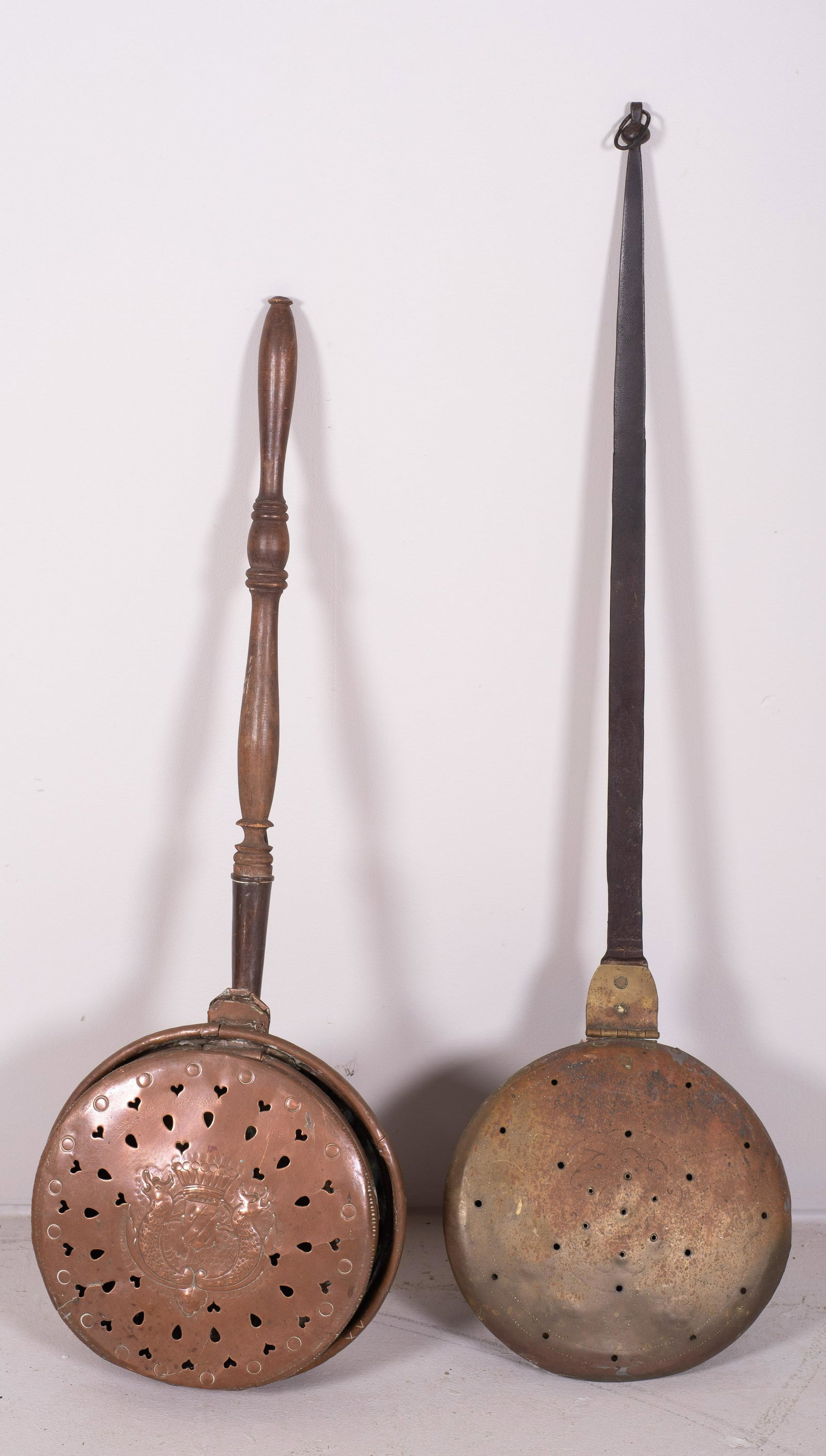 (2) Copper Bed Warmers: (2) Copper bed warmers, (1) in heart and dot pierced dragon and shield decoration, (1) with abstract hammered decoration at top, 38" and 42"