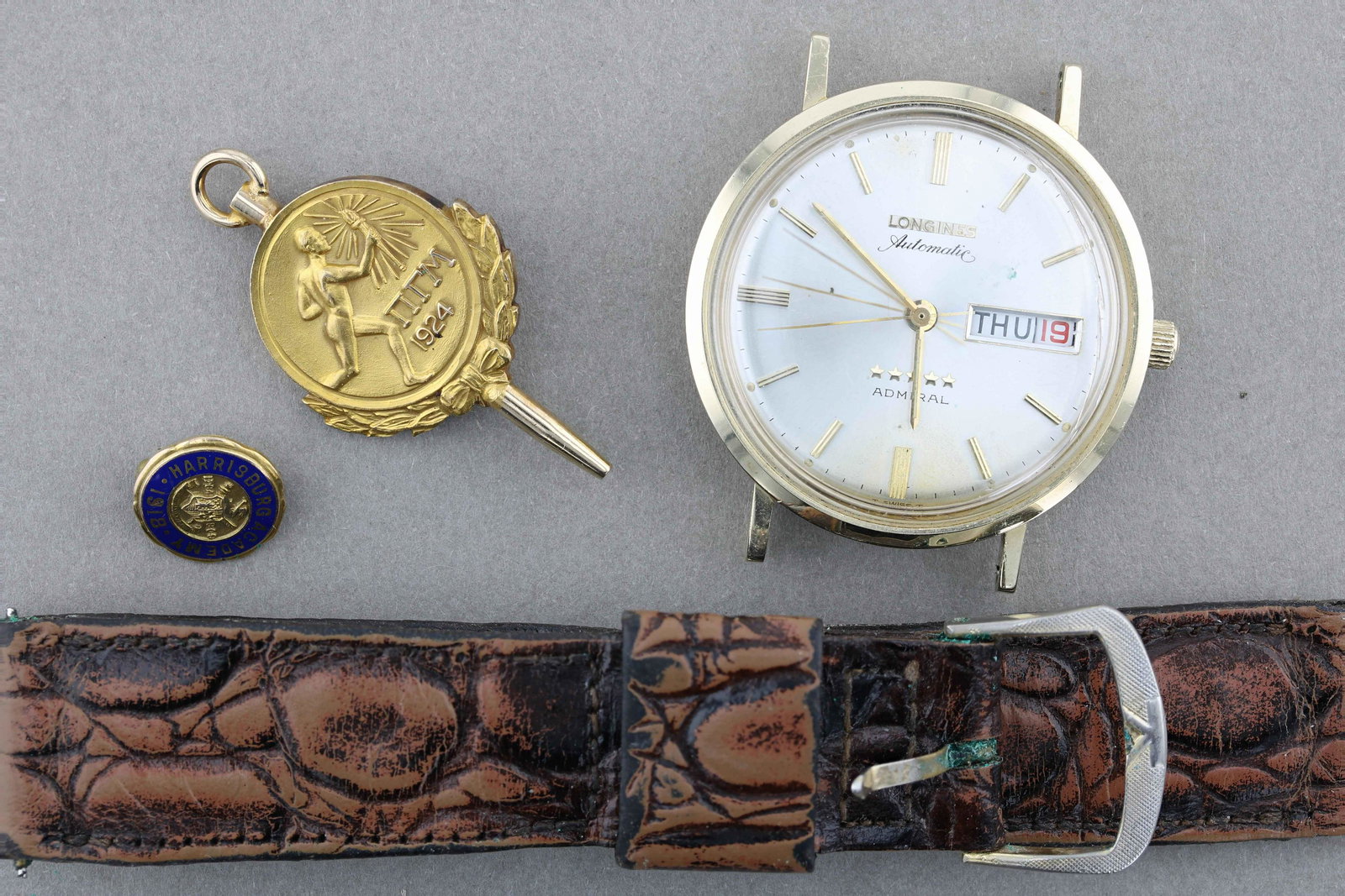 Watch and Pins: Watch and Pin Lot C/O; (1) marked 14K Gold Longines Automatic Watch, Admiral (1) marked 14K Harrisburg academy small round pin, and (1) unmarked gold tone insignia pin, testing at a low 10K. Total wei