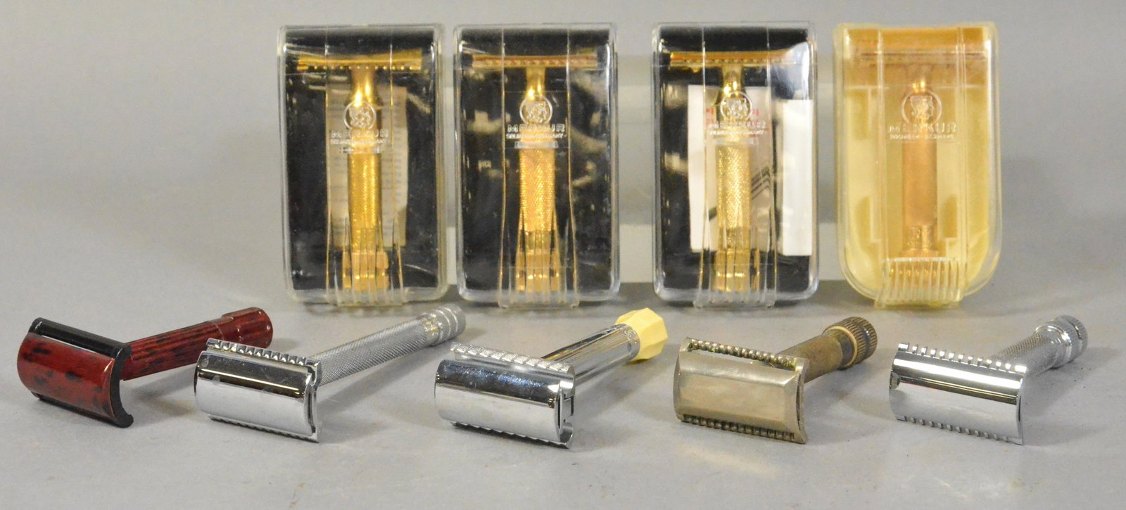 (9) Safety Razors: (9) Safety razors to include (4) gold tone Merkur razors in plastic travel cases, (2) Merkur razors in box, bakelite and metal, and (3) Merkur vintage safety razors.They appear to have some use, would