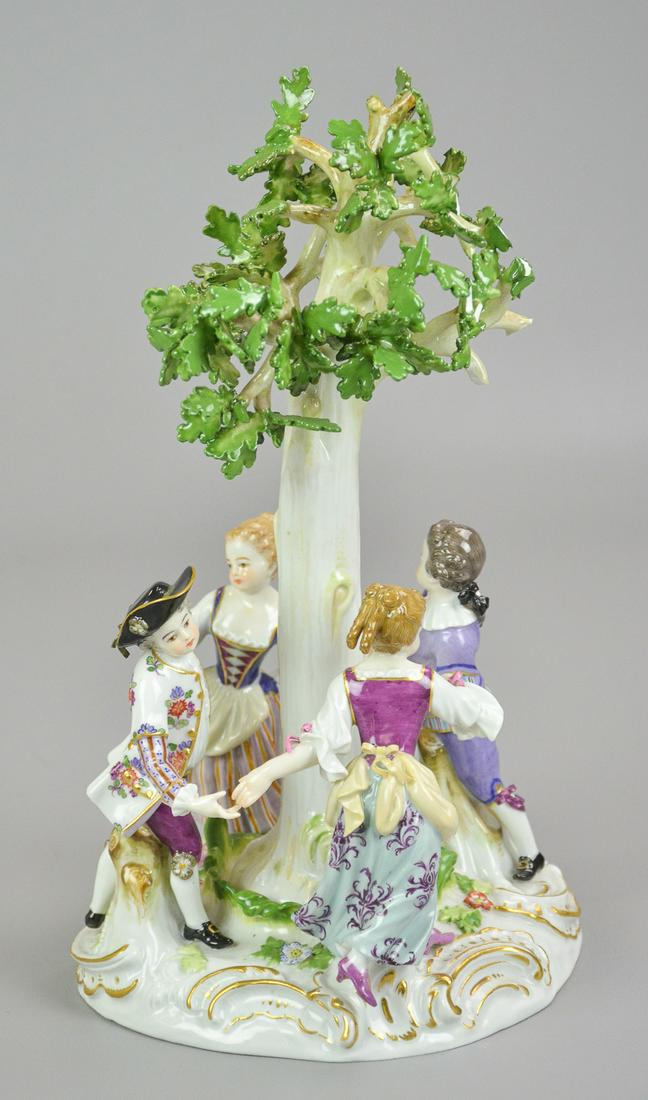 Meissen arbor dancers, 1860-1924,: Figures dancing around a tree, with blue underglaze crossed swords mark.OH 11,", OD 6," broken leaf, loose tree, Chips and loss to tree leaves, bow over boys hat with loss, hairline repair to bottom o