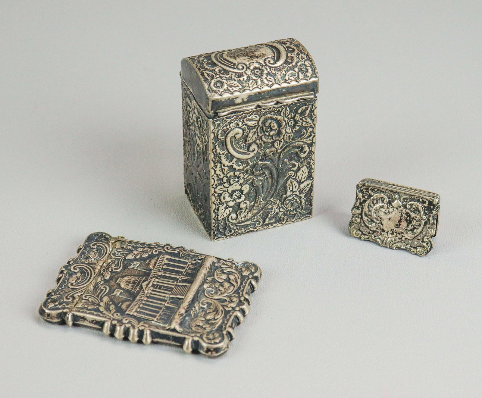 (3) Repousse Silver Articles: (3) Repousse silver articles to include George Nathan & Ridley Hayes Chester silver 1900's repousse dome top box, post in center needs re-attached, unmarked repousse silver card case with state buildi