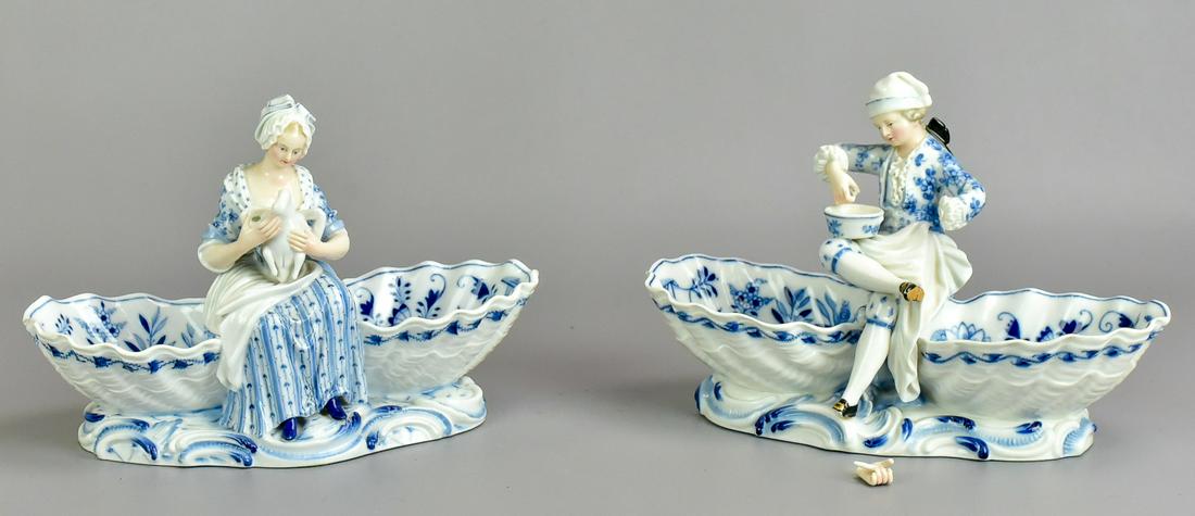 (2) Meissen Figural Double Salts: (2) Meissen figural double salts to include man centered double salt with mixing bowl on knee, in blue decorated ruffle adorned shirt on blue floral decorated shell form salts, broken foot, chipped fo