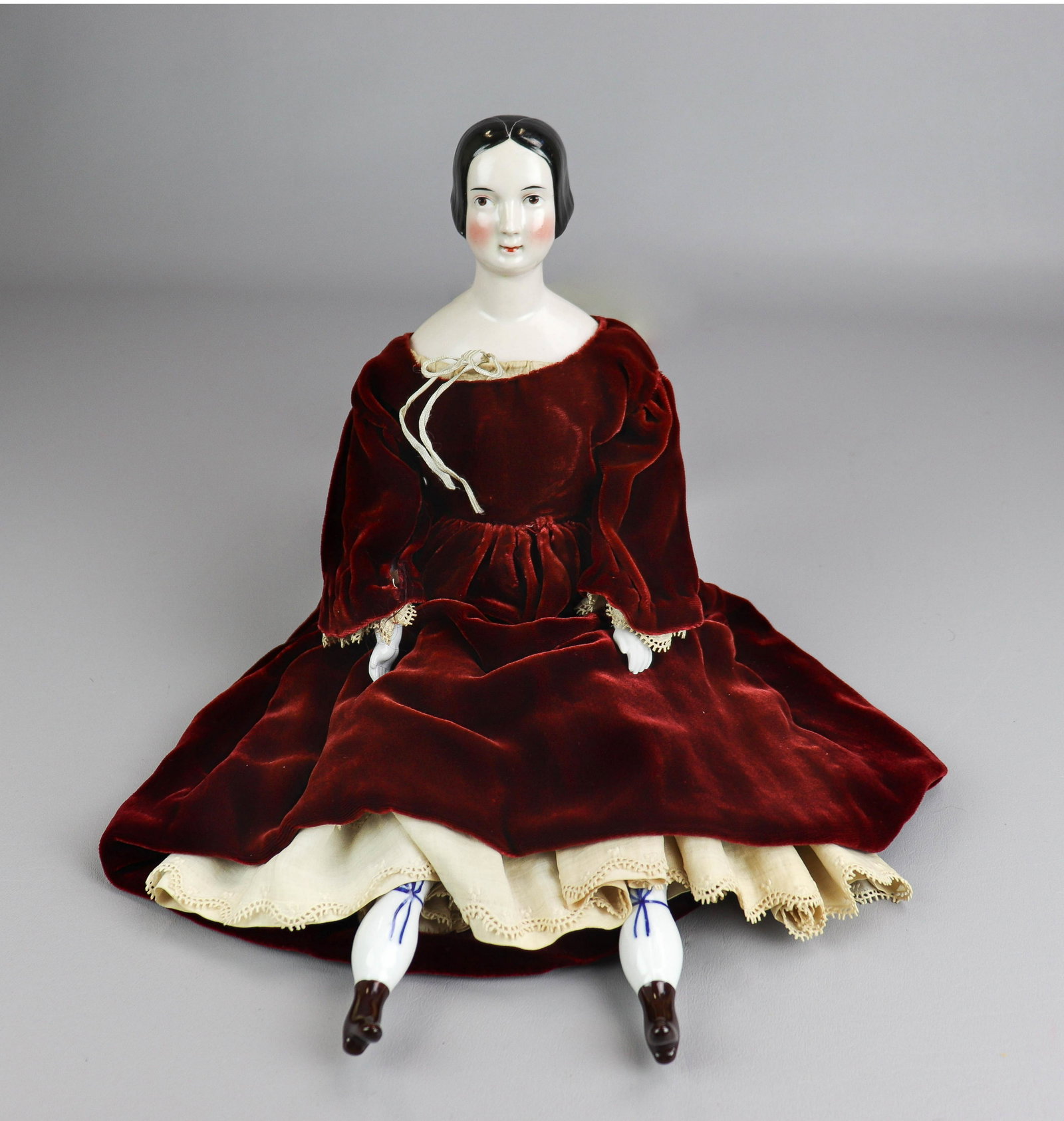 China-Head Shoulder Headed Doll: China-head shoulder headed doll, porcelain arms and legs with painted boots and stocking bows, with stuffed soft body, 19th c, in period correct cotton undergarments and maroon velvet dress, 21" H