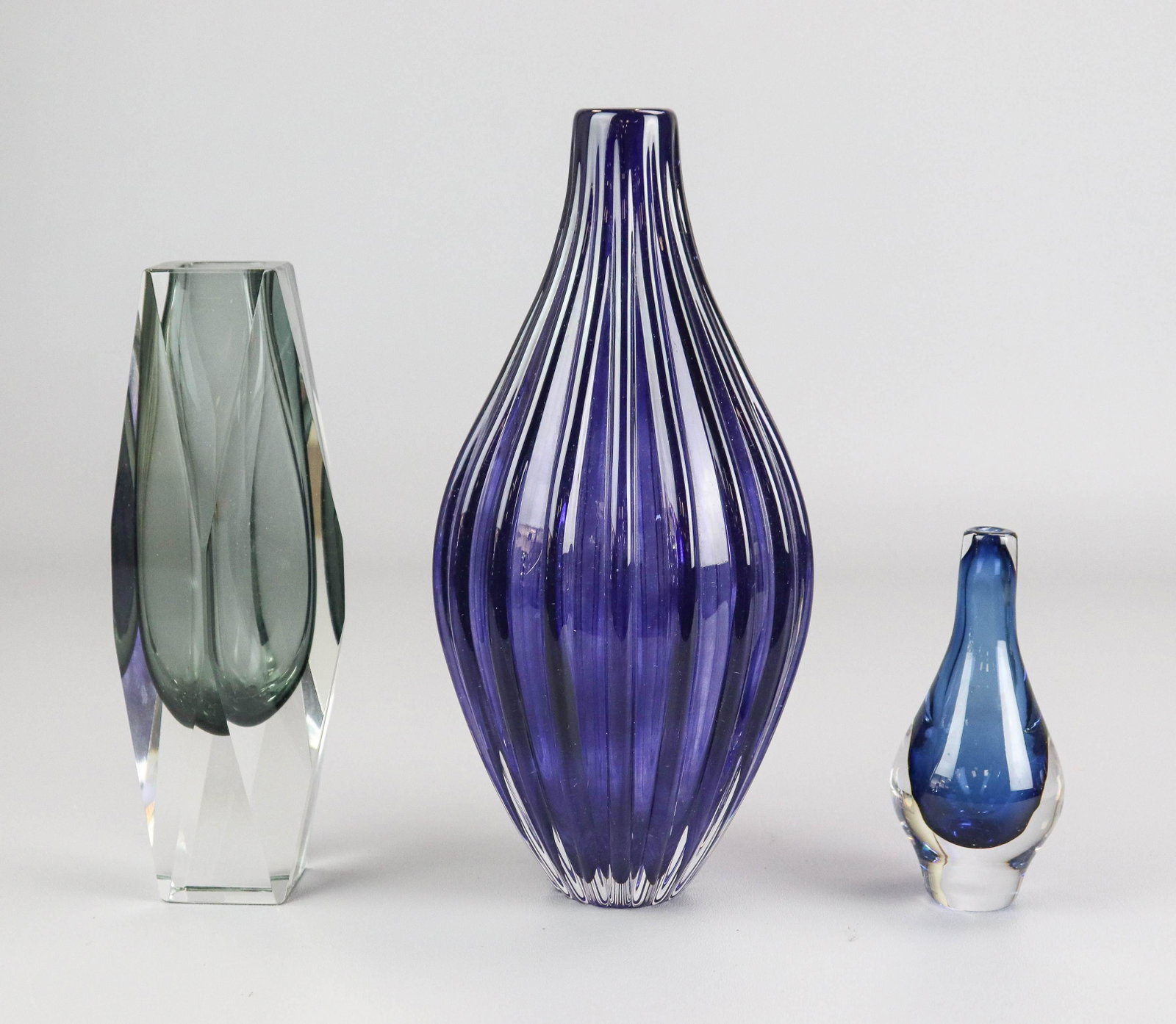 (3) Art Glass Vases: (3) Art glass vases to include Ann Wahlstrom for Kosta Boda ribbed cobalt vase, signed and numbered at underside, 10" h, Murano Mandruzzato smoke gray faceted glass vase, unsigned, 8"h and Mona Morale