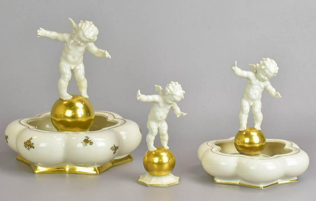 (2) Hutschenreuther Porcelain Flower Frogs: (2) Hutschenreuther porcelain flower frog vases with 3 cherub figurines designed by Karl Tutter, Self Germany, with original paper labels, largest 9" dia x 9" h
