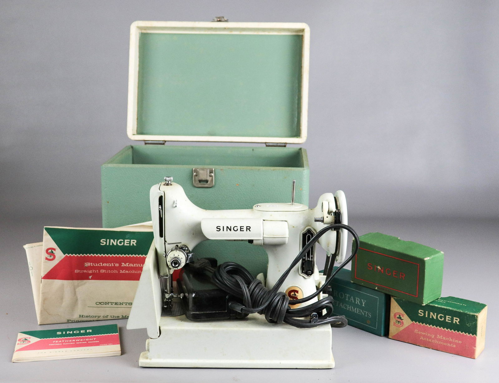 1964 Singer Featherweight Sewing Machine 221K: 1964 Singer Featherweight sewing machine 221K, includes machine, presser foot, bobbin case, students manual, owners manual and assorted attachments, in seafoam case. Motor runs, needle does not go up