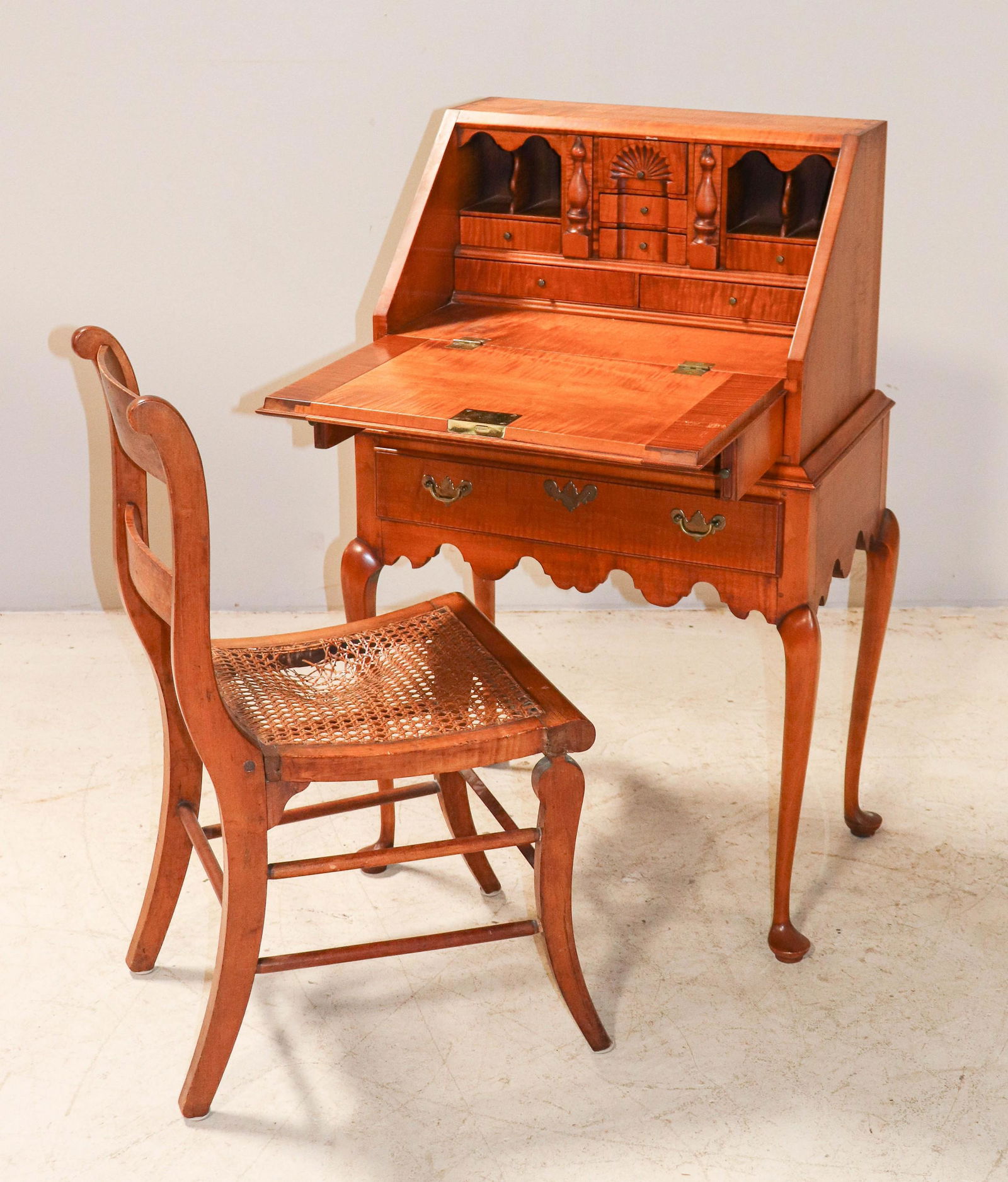 Eldred Wheeler QA style tiger maple slant front ladies: Eldred Wheeler QA style tiger maple slant front ladies desk, fitted interior, over two drawers, scalloped skirt, along with tiger maple caned seat side chair, damage to caning, desk 40-1/2"h x 25"w
