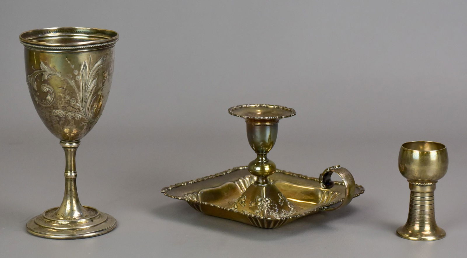 Sterling Candlestick, Shot and Coin Goblet: Sterling candlestick, shot and coin goblet to include sterling scroll and floral decorated hand candle, footed sterling shot, 2-3/4" and coin silver gift goblet given in 1868, engraved in German, 3 T.
