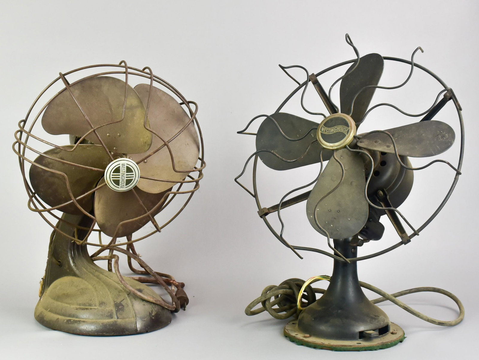(2) Antique Table Fans: (2) Antique table fans to include 1936 Deco Westinghouse fan with 4-bakelite blades, 12" diam and earlier Westinghouse bakelite 4-blade fan, 14" diam, damage to cage, both need rewired.