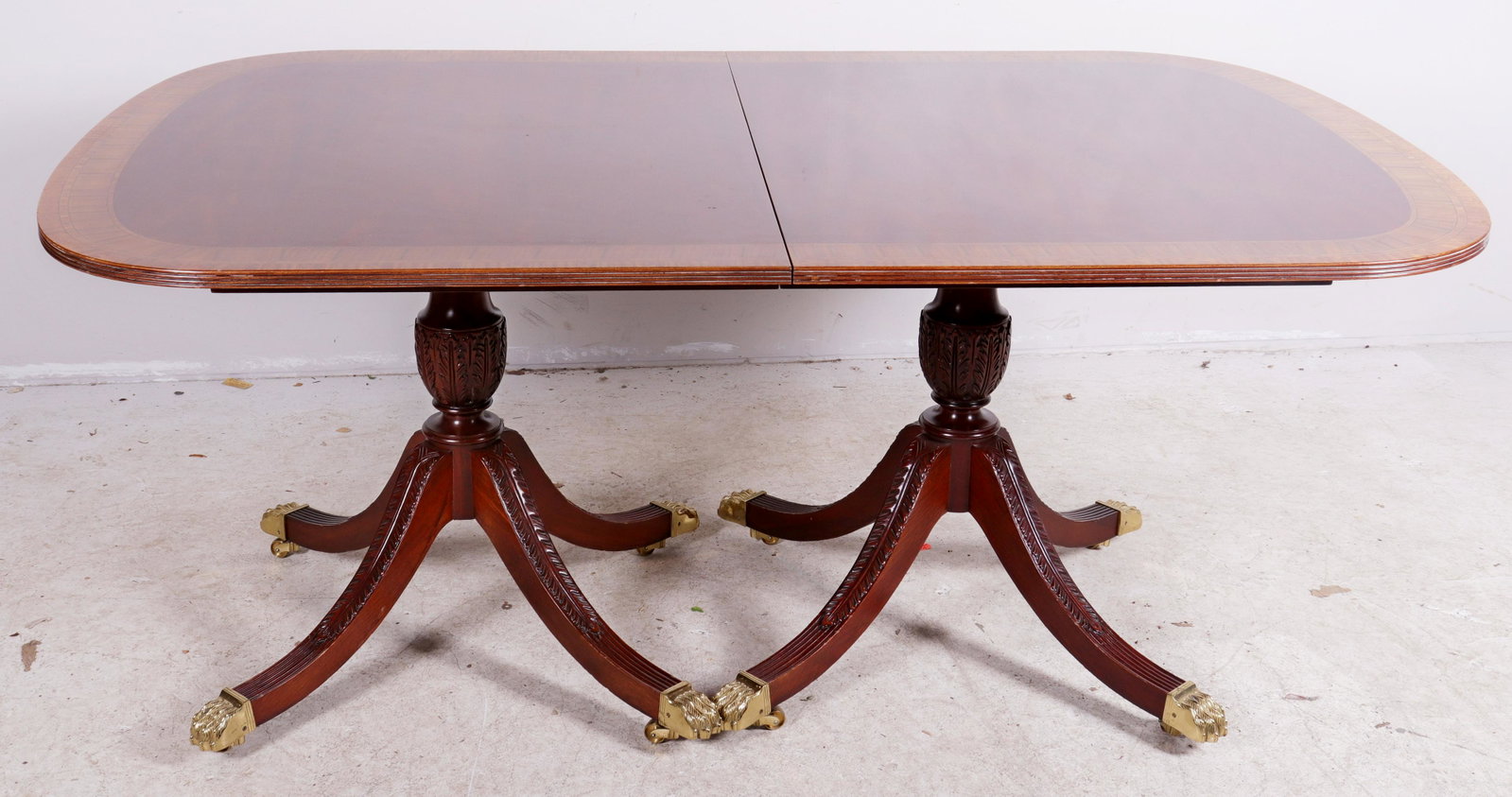 Councill Regency style dining table: Councill Mahogany Regency style dining table, banded top, double pedestal with acanthus decorated legs, brass paw feet, one pedestal missing hardware, 30"h x 71"w x 45"d, three 20"w boards