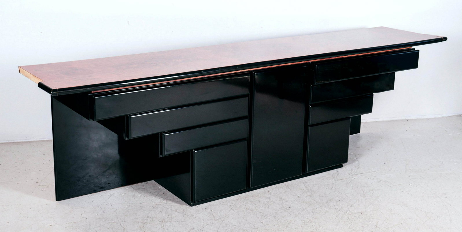 Modern Design laminate console table: Modern Design black and burl laminate console table, center door with interior shelving flanked by ascending drawers, 30"h x 102"w x 20"d, top side cut out, one side needs reattached