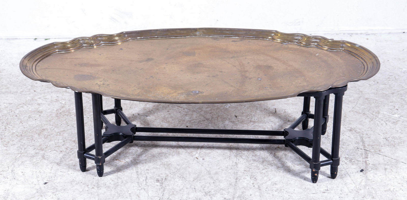 Baker ebonized and brass tray top coffee table: Baker ebonized and brass tray top coffee table, scalloped edge brass tray, ebonized wood stretcher base, 17"h x 55-1/4"w x 32-1/4"d, some light wear to brass, wear to paint on base
