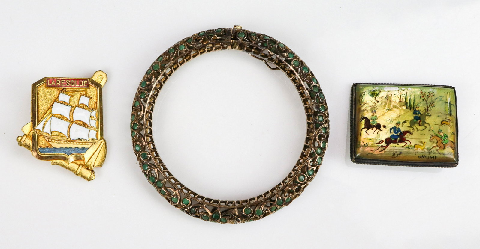 (3) Pc Lot Emerald Bangle and Pins: (3) Pc Lot Emerald Bangle and Pins; (1) Emerald Bangle Bracelet, bass tone, unmarked, missing some stones, (1) Vintage hand painted "Mumi" C clasp pin, 38.8x32.1mm; and (1) vintage gold tone Laresolue