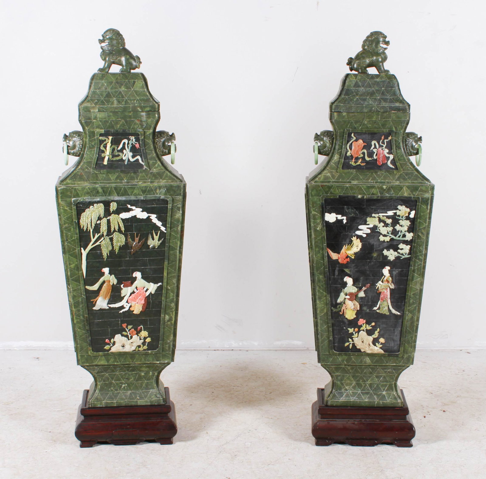 Pair of Chinese Green Hard Stone Urns: Pair of Chinese green hard stone urns, applied stone figures in landscape and floral decoration, foo lion finials, foo dog handles, on wood stands, 60" h x 18" w x 11" d
