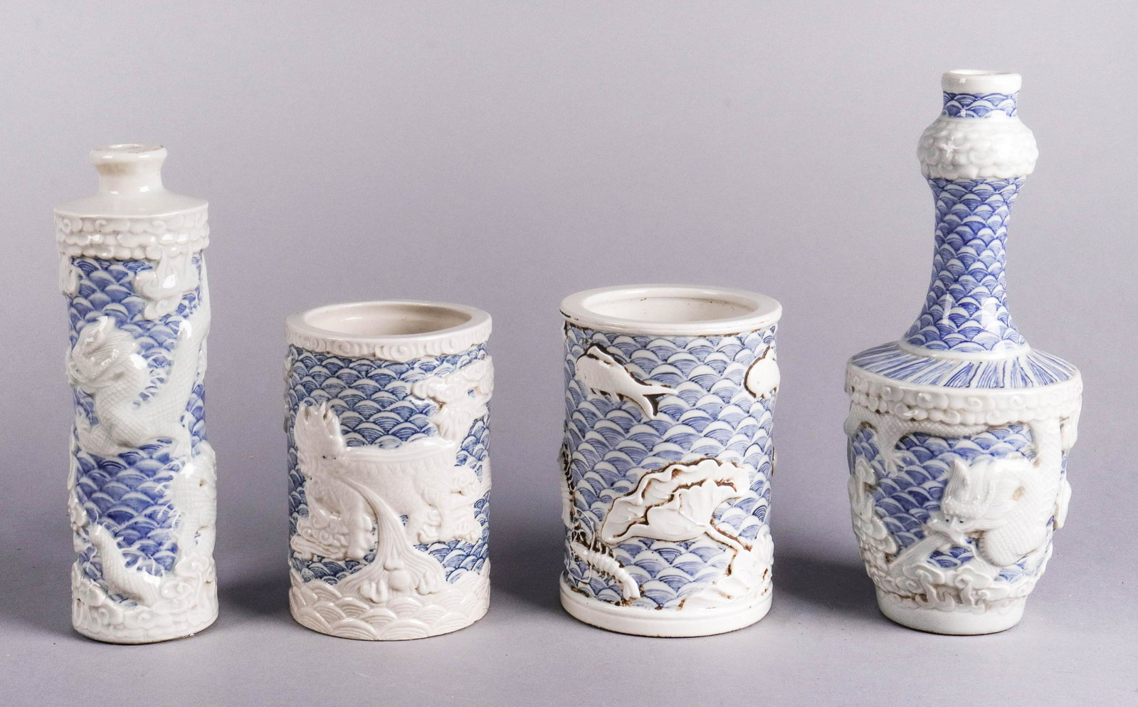 (4) Pcs Wang Bingrong Dragon & Waves Porcelain: (4) Pcs Chinese carved porcelain, "Waves" pattern bearing mark of Wang Bingrong, c/o 9" dragon garlic mouth vase, 8-1/4" dragon bottle, 5-1/2" x 4" dia fish & lobster brushpot, 5-1/4" x 3-3/4" dia dra