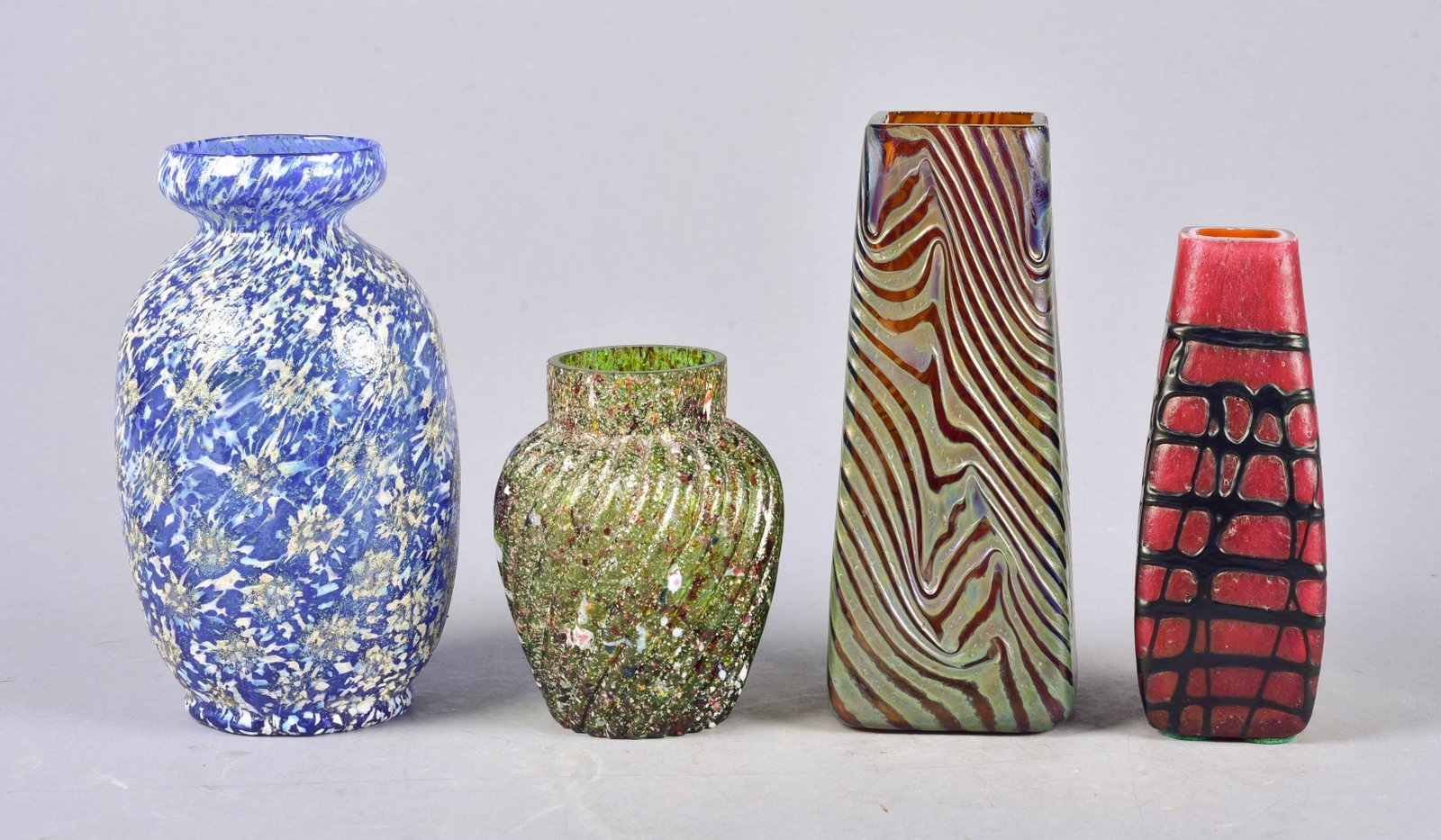 (4) Art Glass Vases: (4) Art glass vases to include Dugan style green swirled spatter glass vase, flakes at rim, 4"h, Dugan snowflake pattern spatter glass vase, 6"h, tapered square glass vase with lustre threading, Rinds