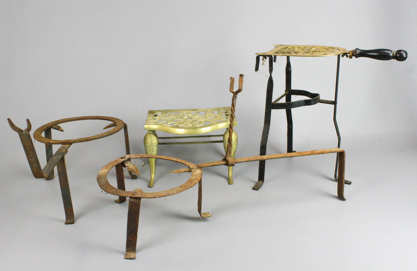 (4) Fireplace Trivets: (4) Fireplace trivets, c/o brass & wrought iron (6-/8" x 14-1/4" x 13-1/2" h, brass with pierced bird decoration (9-1/2" x 7" x 6" h, wrought iron with fork handle (9" x 21" x 12-5/8" h overall), wrou