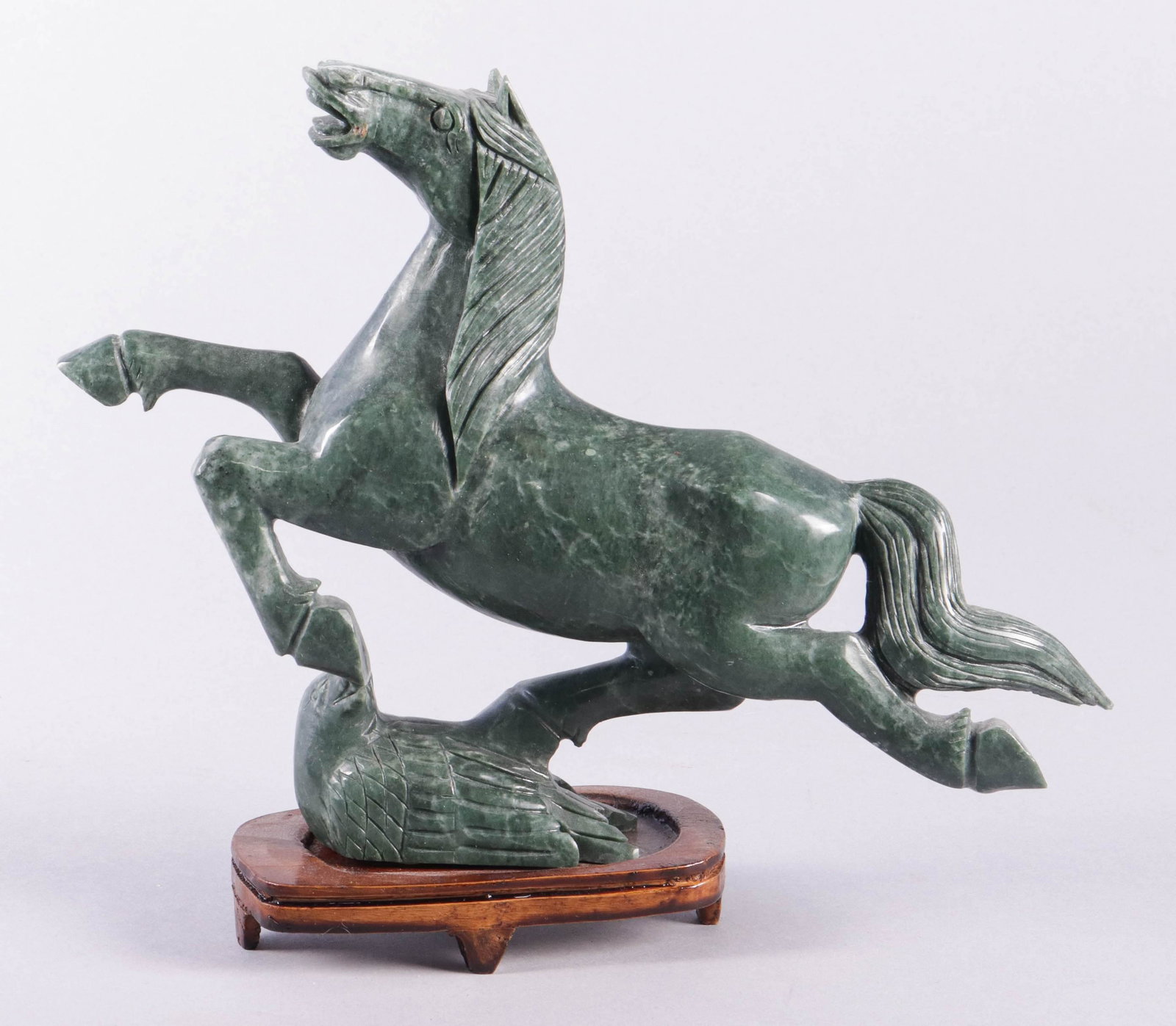 Chinese Gansu Flying Horse Figure: Chinese carved green stone Gansu flying horse figure on wood stand, 9-1/4" h x 11" w