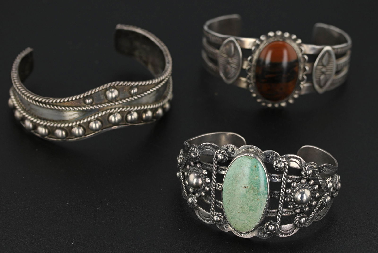 (3) South Western Cuff Bangles: (3) Silver cuff bracelets, (1) cuff bracelet sterling silver braided and dome details; "I.W Mexico 925" approx. 20mm wide; (2) Coin silver cuff bracelets, greenish turquoise, 38.1mm top; (1) 34.6mm to