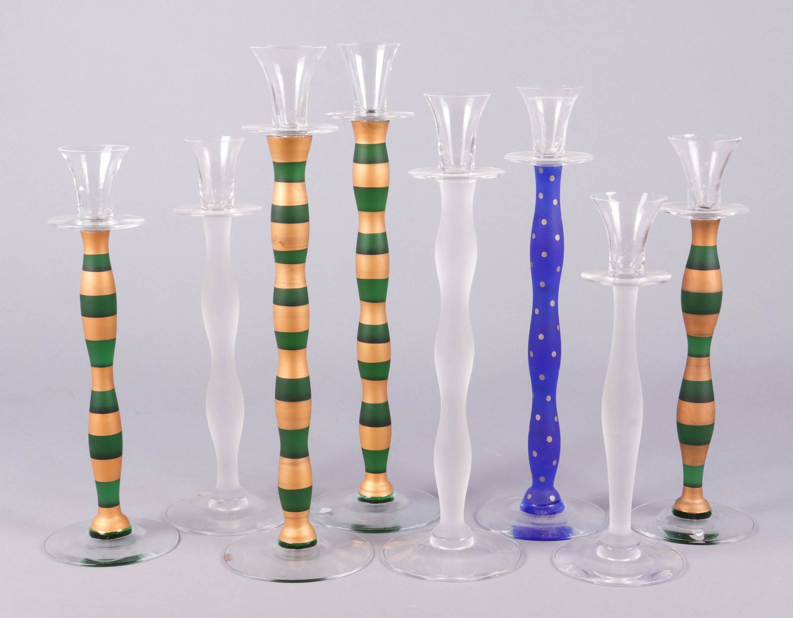 (8) Orrefors Anne Nilsson Candlesticks: (8) Orrefors Anne Nilsson candlesticks to include (3) frosted graduated candlesticks, 11-3/4" H, 13" H, 14-3/4"H, (1) blue frosted dot decorated stick, 14-3/4" H and (4) green and gilt frosted sticks,