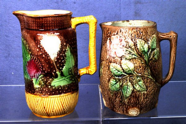 2 majolica pitchers, floral and leaf patterns, 8",: 2 majolica pitchers, floral and leaf patterns, 8", 7" in height, smaller one with a rim flake & 1" inside hairline