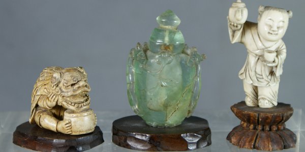 Pale green floral carved stone snuff bottle with i: Pale green floral carved stone snuff bottle with interior fractures, 2 5/8" h, with a carved ivory figure of a man holding a foodog mask, 1 3/4" l, with an ivory carved figure missing his hat, 2 1/4" 