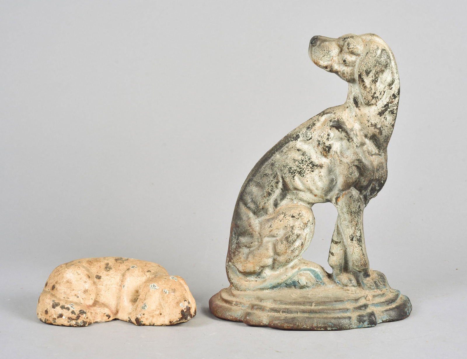 (2) Cast Iron Dog Form Doorstops: (2) Cast iron dog form doorstops to include seated hound, 12" H x 9" W and white painted cast iron laying hound, 7" L