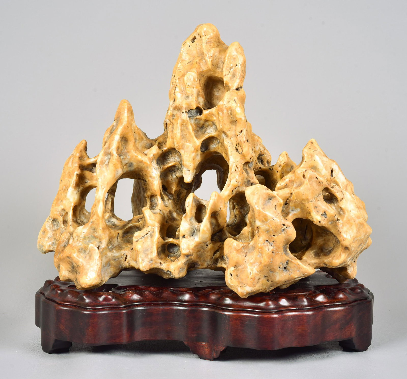 Chinese Gongshi Carved Stone: Chinese Gongshi carved stone with fitted hard wood stand, 11" h x 15" w, The base is fitted, made for the piece