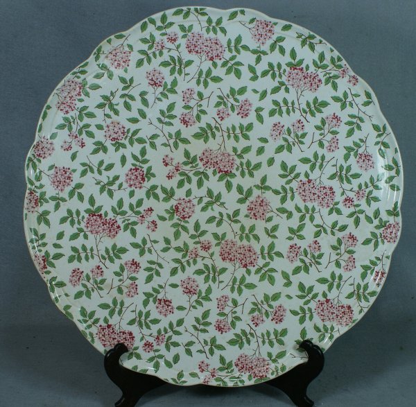 Minton's porcelain round scalloped tray with a gre: Minton's porcelain round scalloped tray with a green and pink floral spray overall design, impressed Minton's mark, retailed by AB Daniell and Son, 46 Wigmore Street, London, 22" diameter, light even 