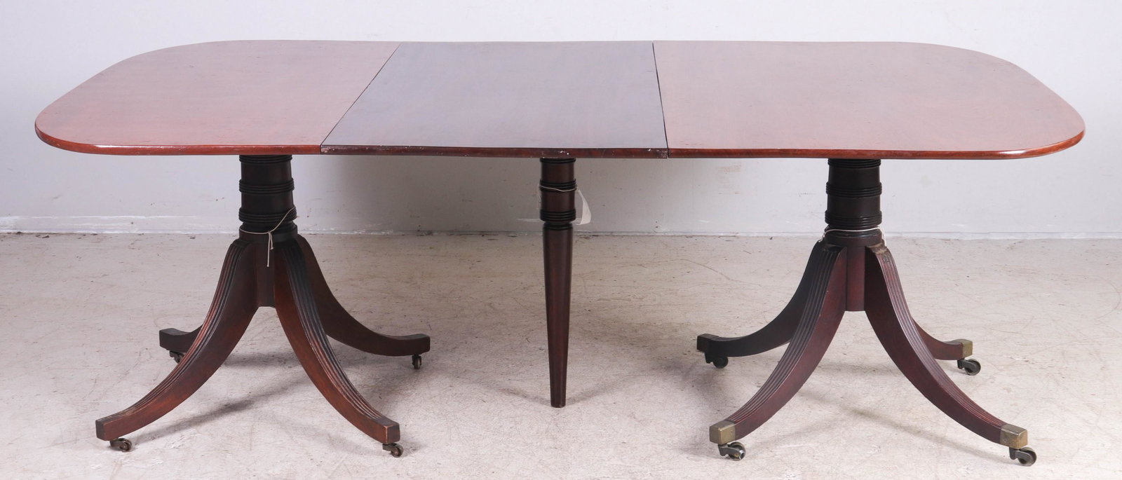 2-part Duncan Phyfe dining table: 2-part Duncan Phyfe dining table, each pedestal with reeded sabre legs with brass tips on casters, top with rounded corners, 65"l x 52-1/2"w, one 25-1/2"w leaf 90-1/2" extended, mid 19th c