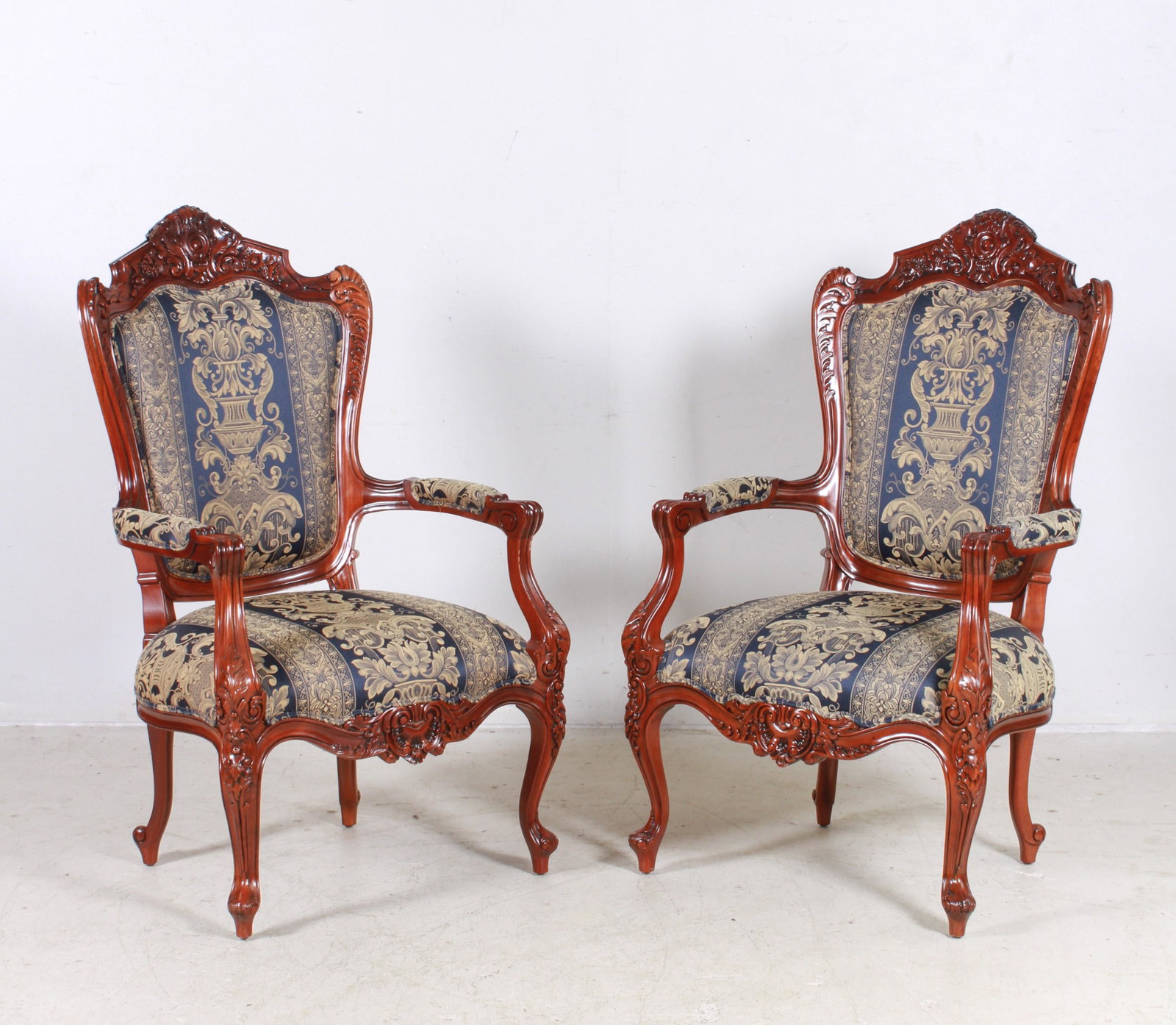 Pair Italian style oversized carved mahogany open: Pair Italian style oversized carved mahogany open armchairs, acanthus carved decoration around frame, blue and gold urn form and acanthus striped upholstery, 49"h x 27"w x 23"d