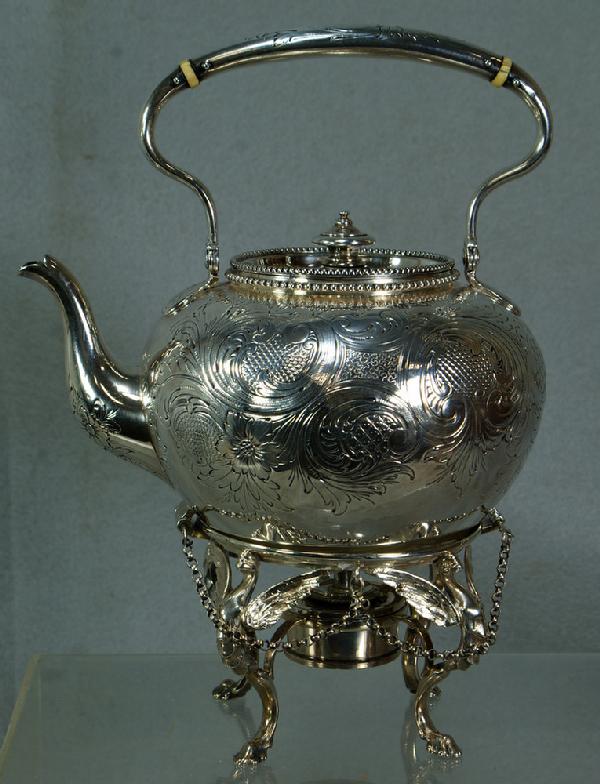 Early Tiffany & Co, Makers sterling silver engrav: Early Tiffany & Co, Makers sterling silver engraved tilting teapot on stand, Moore marks, 550 Broadway address, engraved foliate design, winged phoenixes supporting the base, swing handle, 29.37 TO, a