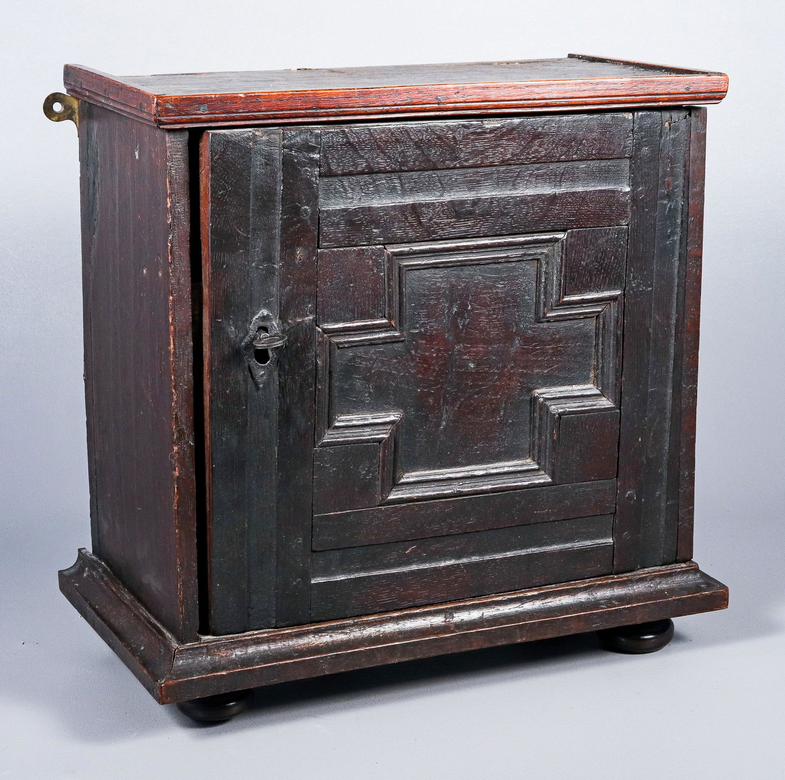 English oak and elmwood spice cabinet: English oak and elmwood spice cabinet, single panel door with hand wrought iron hardware, concealing an interior with 7 drawers around a central drawer, raised on bun feet, old surface, 17th c, 15-3/8