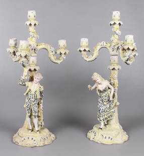 German Bisque Dresden Figural Candelabra Pair: German bisque Dresden figural candelabra pair, after C.G. Schierholz & Sohn, to include bisque male and female figural candelabras, scroll and tree decorated base with figures in coordinated blue and