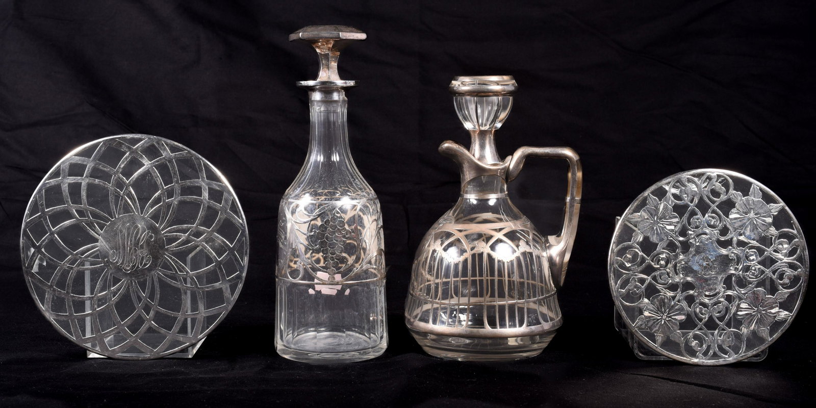 Sterling Clad Decanters and Trivets: Sterling clad decanters and trivets to include sterling clad decanted, handled, in garland decoration, monogram at front, 9" h, sterling clad grape decorated decanter with monogram at front, 10-1/2" H