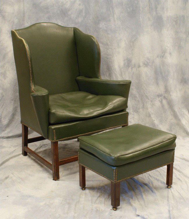 English Chippendale stretcher base wing chair, uph: English Chippendale stretcher base wing chair, upholstered in green leather, with a similar green footstool, 47"h