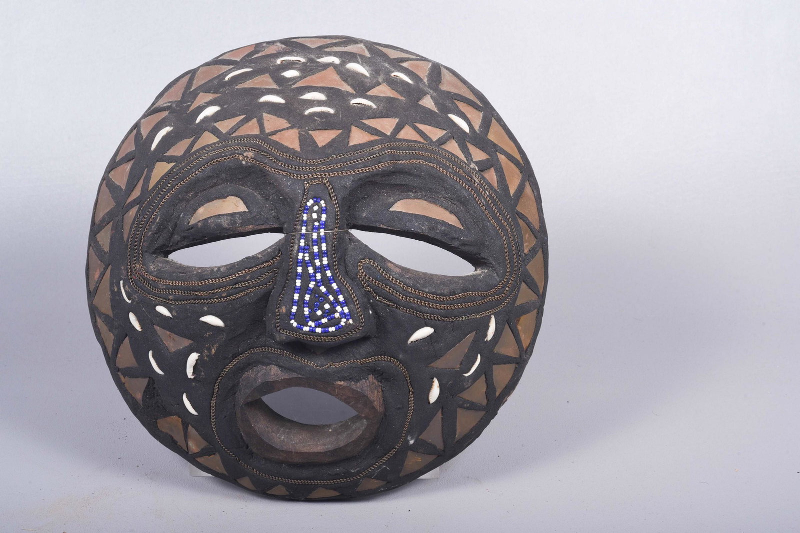 Carved wood African mask: Carved wood African mask decorated with seed beads, copper & cowrie shells, 11" x 11-1/4"