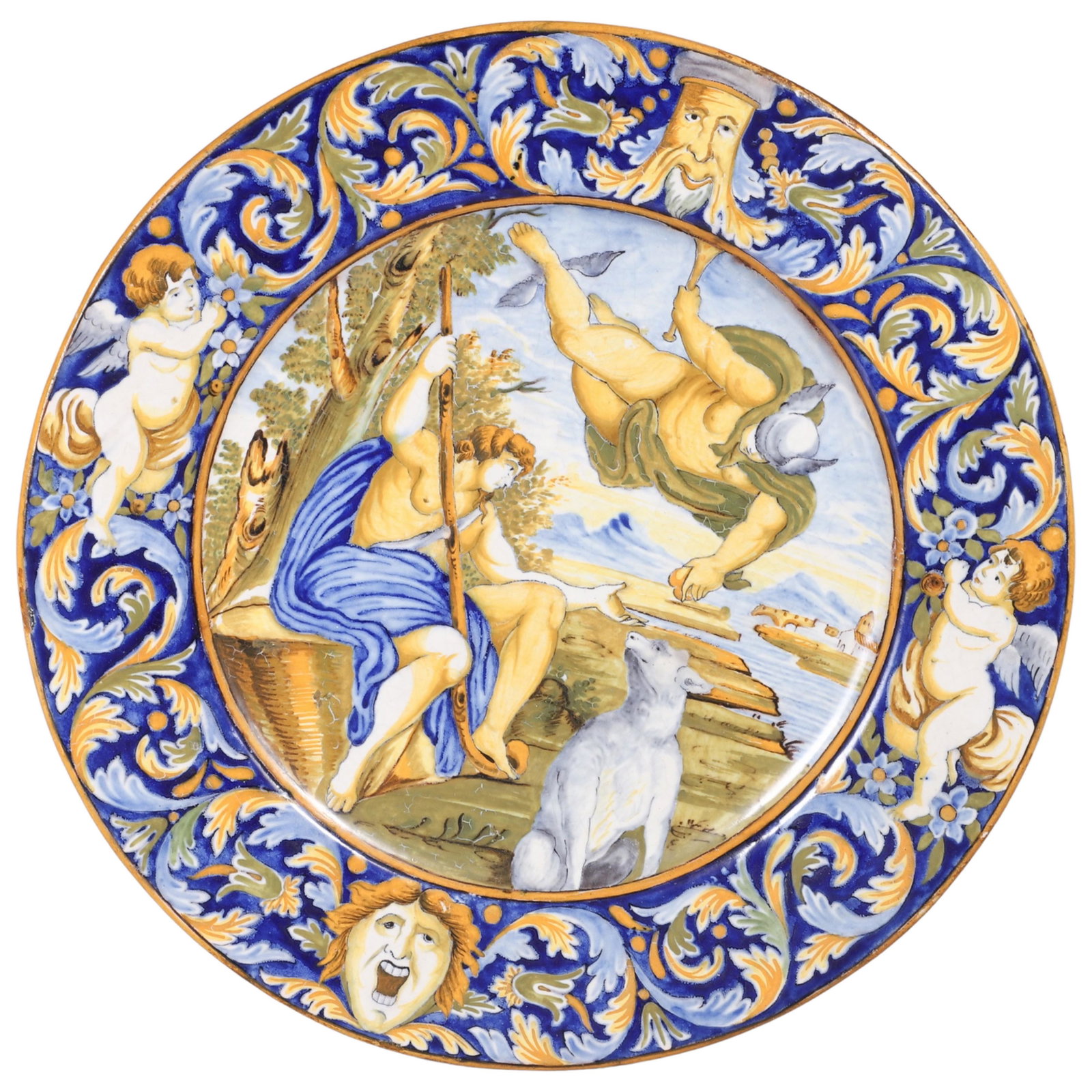 Tin Glazed Faience Charger: Tin Glazed Faience Charger, floral cobalt border with cherubs and faces, the center where the scene of a mythical figure delivering an apple to another seated figure with a sheep in foreground, all in