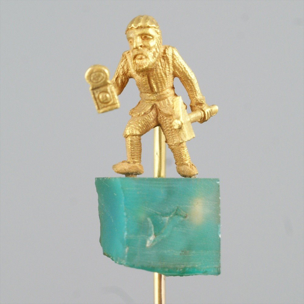 Unmarked YG stickpin, bearded man with hammer an: Unmarked YG stickpin, bearded man with hammer and clock, on green stone block, 2.5 dwt