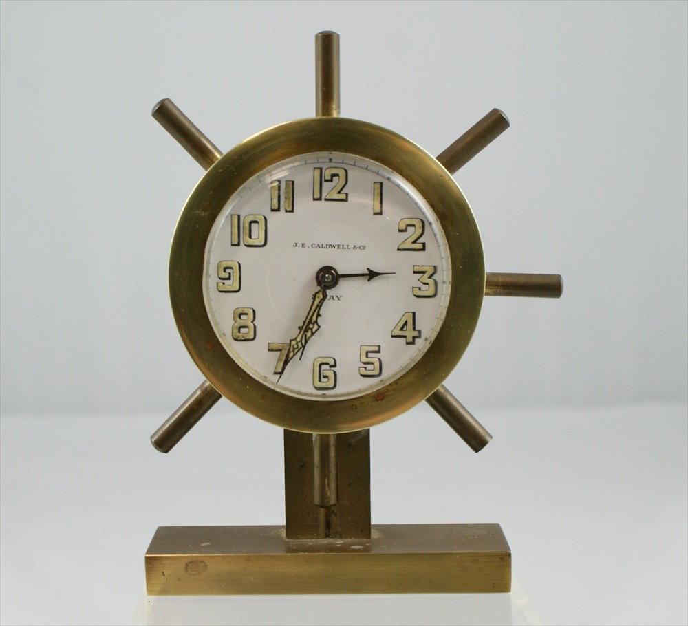 JE Caldwell ships wheel 8 day alarm clock, winds: JE Caldwell ships wheel 8 day alarm clock, winds but does not run, missing one spoke on the wheel, 4 3/4" high, 2" sunken dial