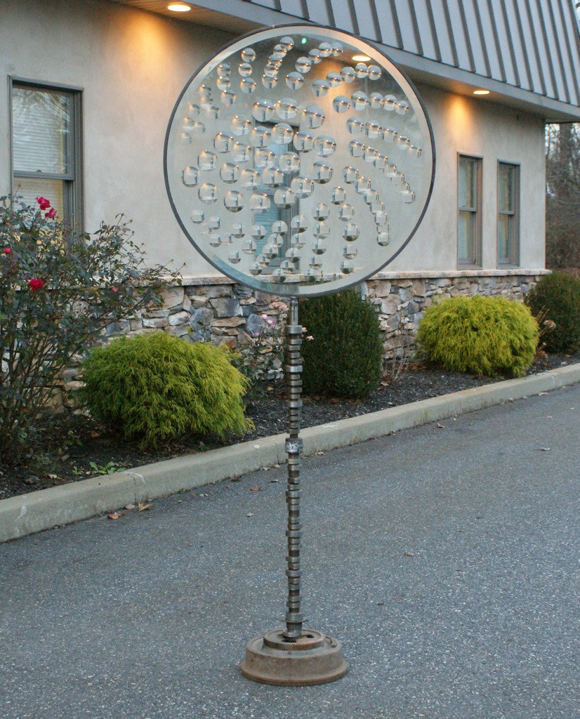 Feliciano Bejar, Mexican/American, 1920-2007, Ma: Feliciano Bejar, Mexican/American, 1920-2007, Magicscope sculpture, large circular panel, 32 1/4" d, 63 1/2" tall, on a base made from auto gears and splines, signature and date 2001 etched on glass