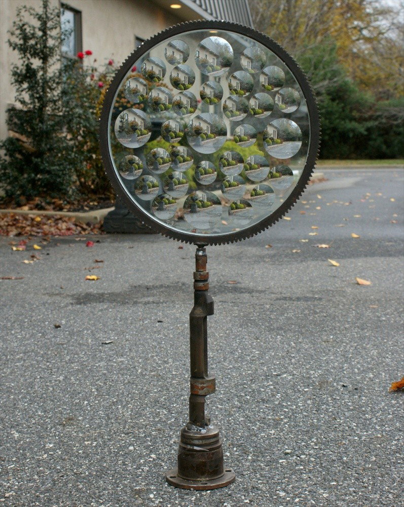 Feliciano Bejar, Mexican/American, 1920-2007, Ma: Feliciano Bejar, Mexican/American, 1920-2007, Magicscope sculpture, small circular panel, 14 1/4" d, 29 1/2" tall, on a base made from auto gears and splines, signature and date 2001 etched on glass