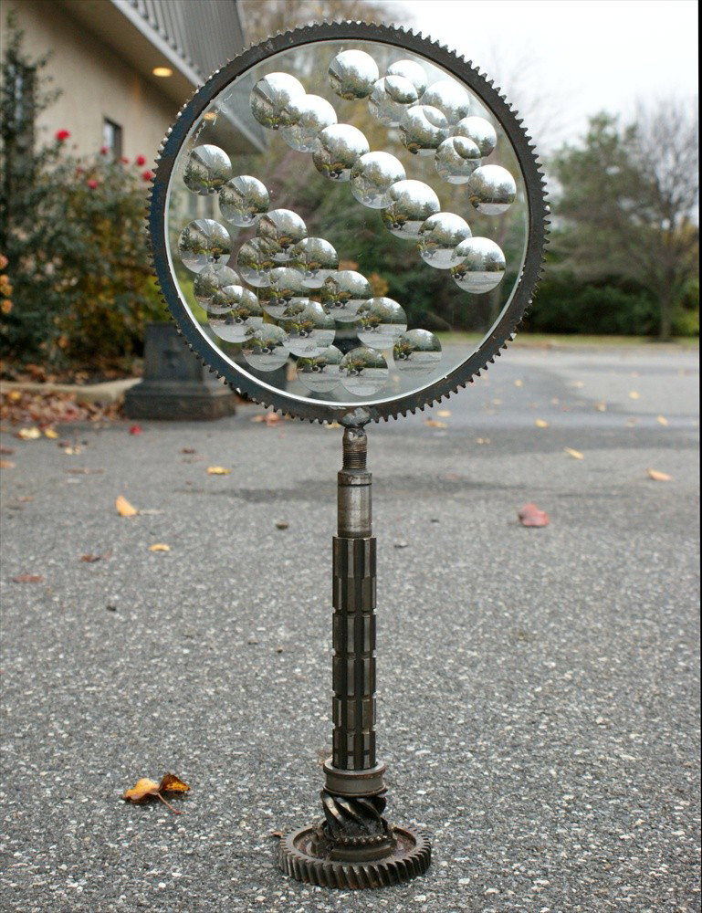 Feliciano Bejar, Mexican/American, 1920-2007, Ma: Feliciano Bejar, Mexican/American, 1920-2007, Magicscope sculpture, small circular panel, 11 1/2" d, 24" tall, on a base made from auto gears and splines, signature and date 2001 etched on glass