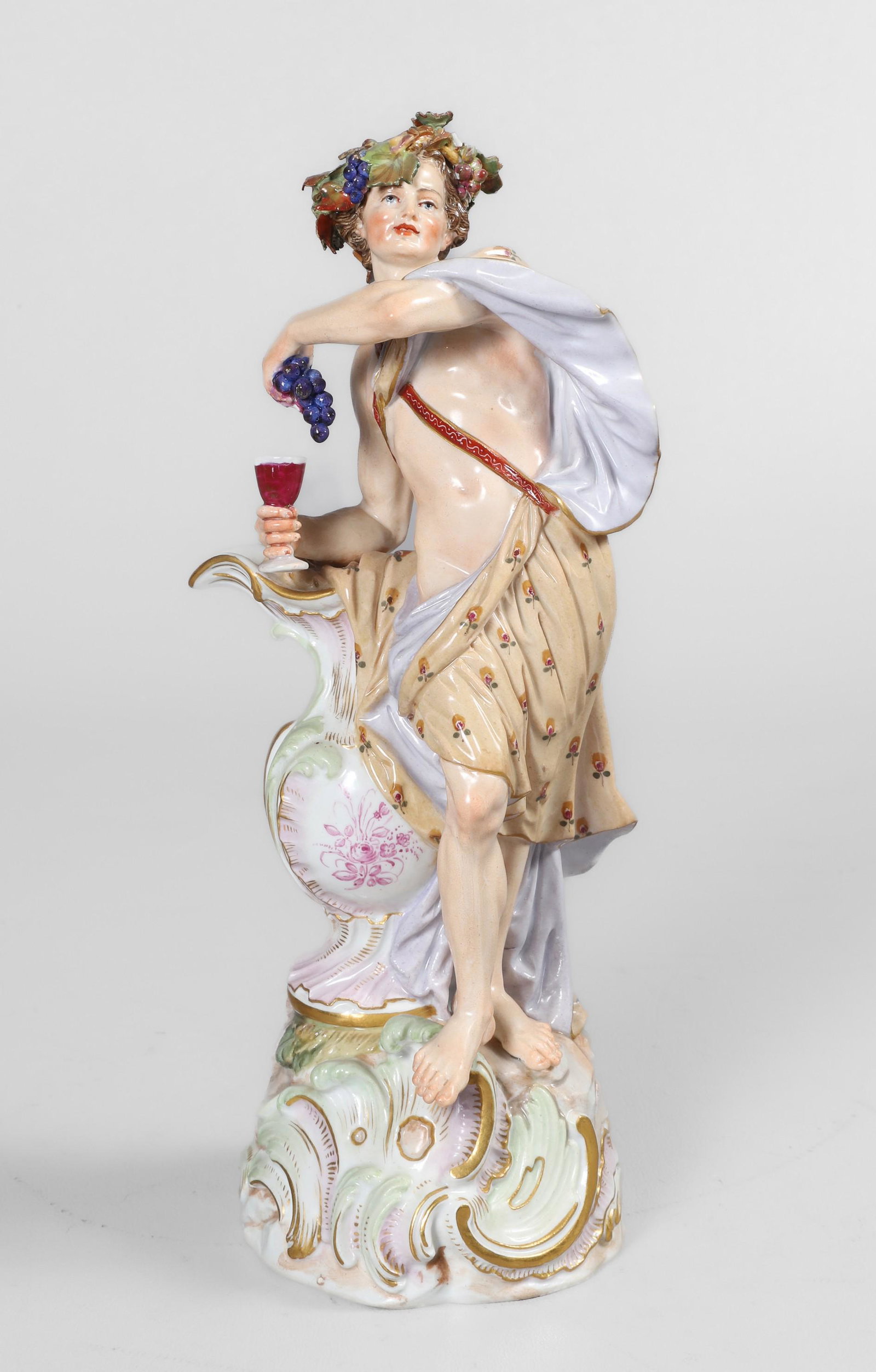 Meissen Porcelain Figure of Bacchus: Meissen Porcelain Figure of Bacchus, late 19th c figure of an ornately robed bacchus leaning on oversized vessel with wine and grape at hand, crowned with grape vine, leaf and fruit, on scroll base wi