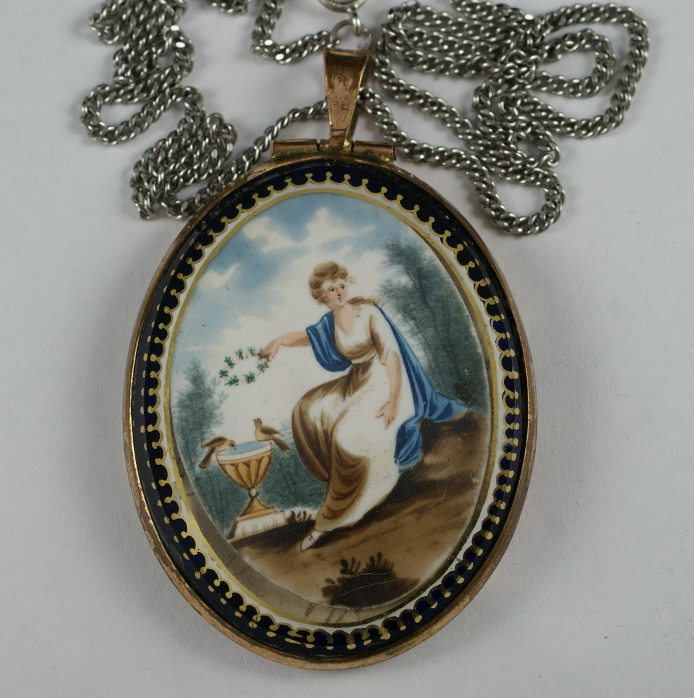 Oval HP ivory mourning locket/pendant depicting: Oval HP ivory mourning locket/pendant depicting seated lady holding a wreath over a bird bath, 2" h, 1 1/2" w, on a later sterling chain, interior lined with purple fabric, back glass loose, sold subj